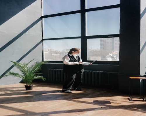 A person taking a standing break near a bright window in an office